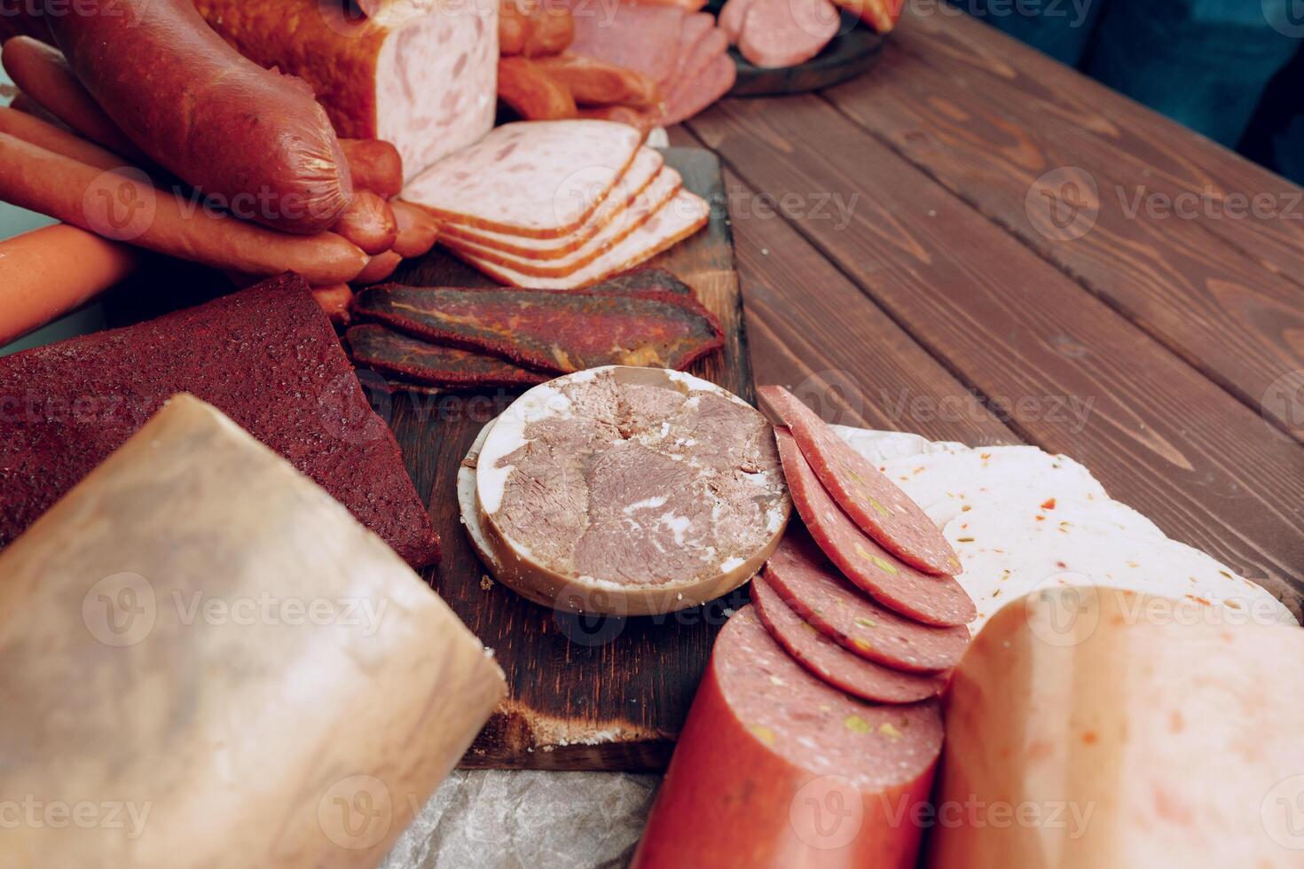 Assortment of different sausages laid out on brown wooden background photo