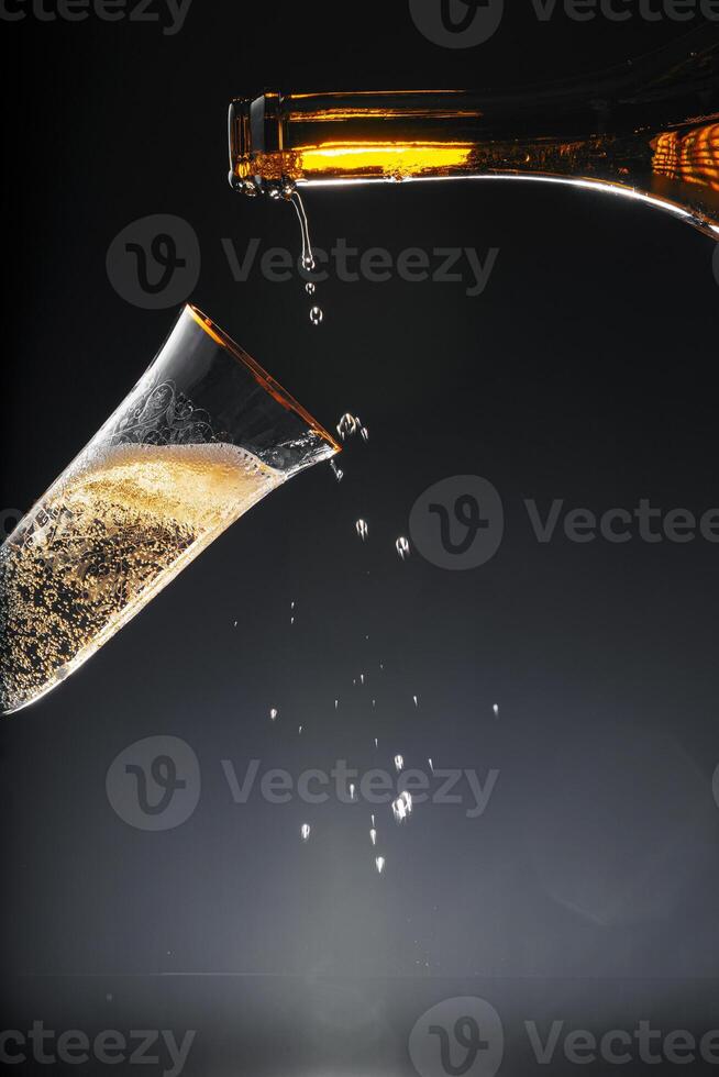 Champagne pouring into glass on black background photo