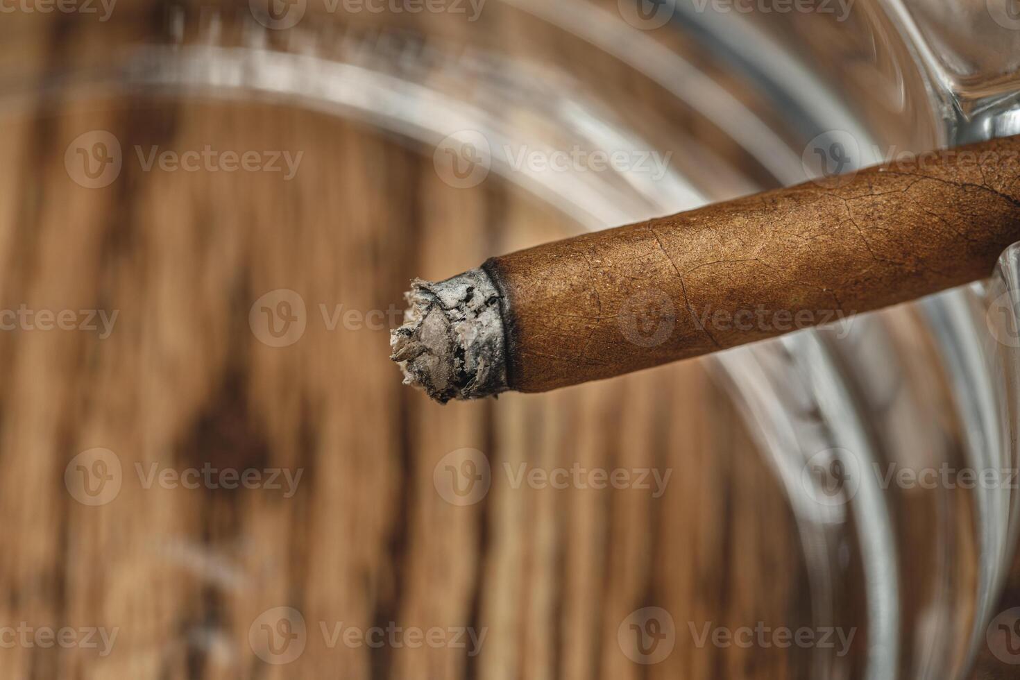 Lighted cigar in an ashtray close up photo