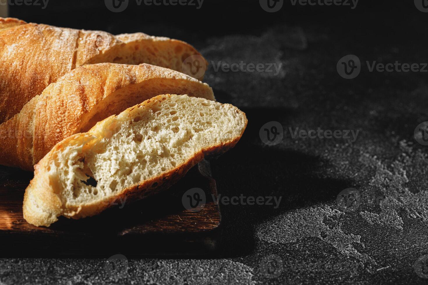 Sliced baguette bread on wooden board close up photo
