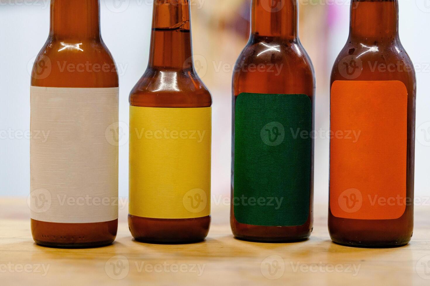 Four brown glass bottles with different colored labels sit on a wooden table photo
