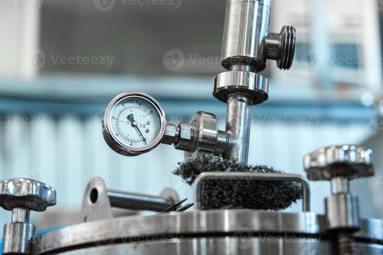 A pressure gauge on a stainless steel tank in an industrial setting displays the pressure reading photo