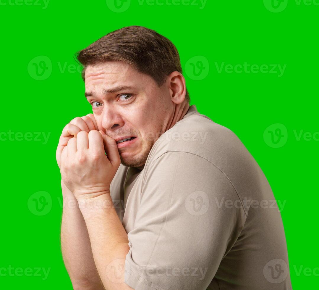 Man expressing fear while standing against a bright green background photo