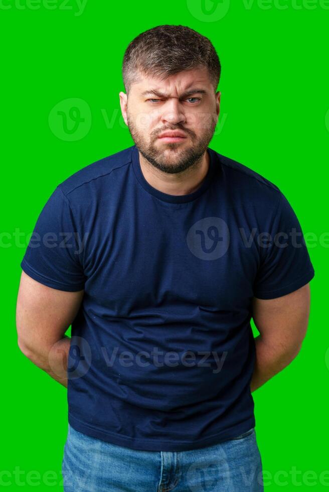 Man expressing confusion with crossed arms in front of a bright green background photo