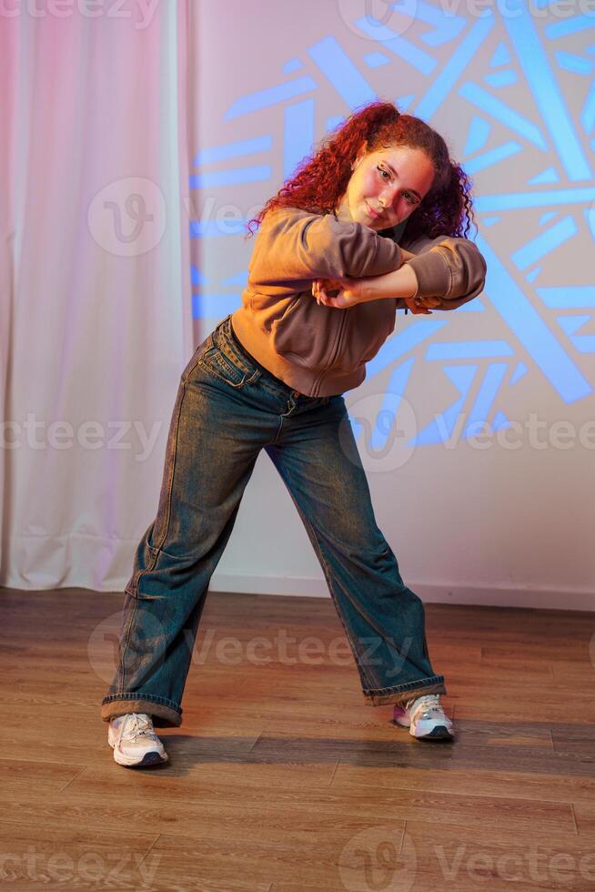 A young woman with red hair dances in a studio, her body contorted in a dynamic pose photo