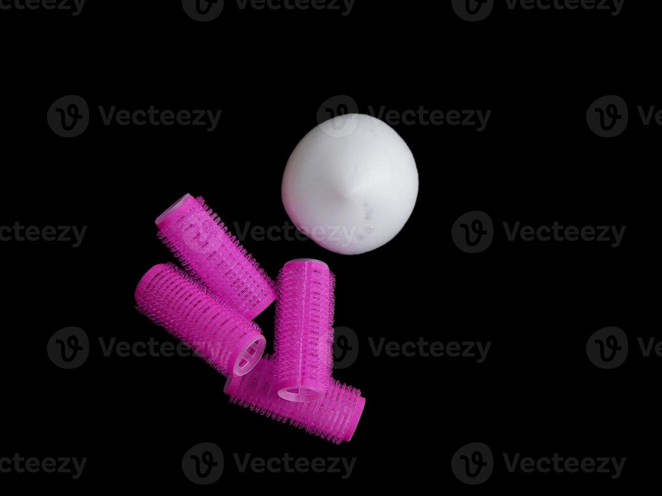 Products for hair styling - curlers and volume styling mousse isolated on black background with copy space photo