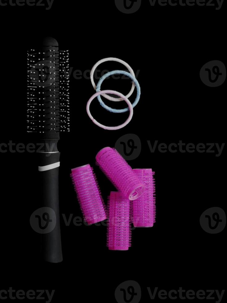 Different products for hair styling - comb, curlers and hair bands isolated on black background with copy space photo
