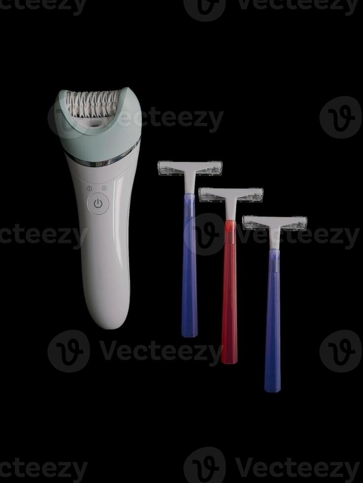 Different products for removing body hair - razor and epilator isolated on black background with copy space. Concept of choice and comparison photo