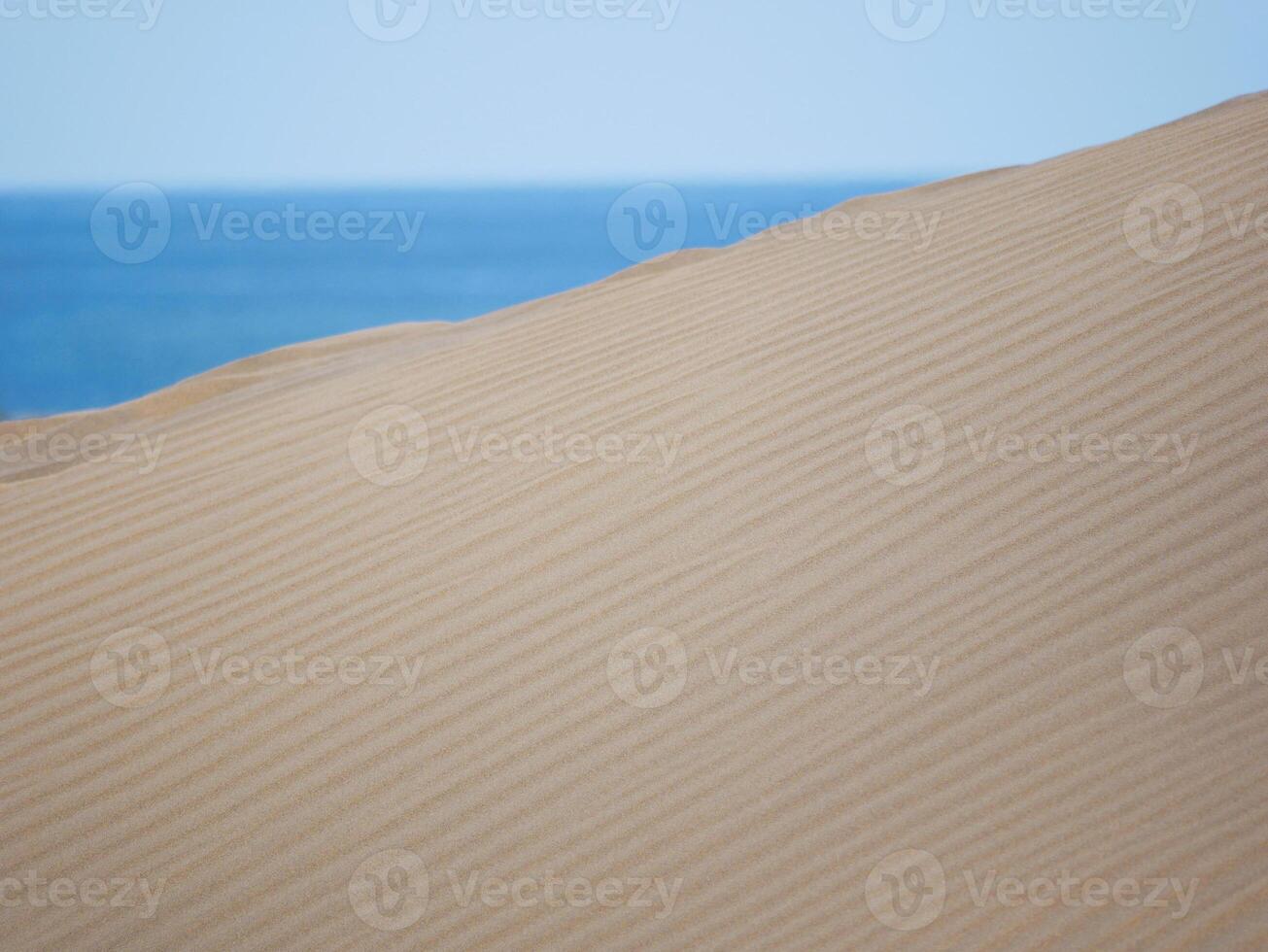 Sand textured pattern with copy space close up in Maspalomas, Gran Canaria. Abstract background wallpaper. Sand waves in a desert dune at the background of the sea photo