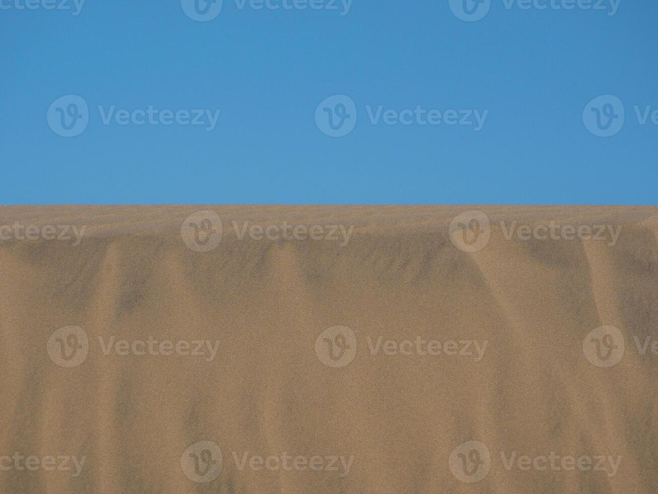 Sand textured pattern with copy space close up in Maspalomas, Gran Canaria. Abstract background wallpaper. Sand waves in a desert dune against the sky photo