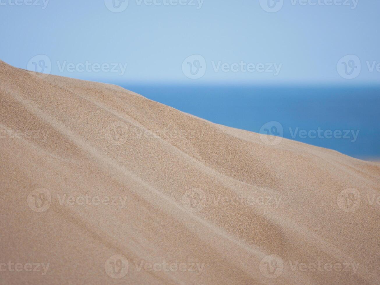 Sand textured pattern with copy space close up in Maspalomas, Gran Canaria. Abstract background wallpaper. Sand waves in a desert dune at the background of the sea photo