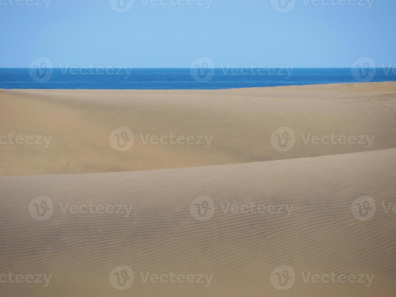 Sand textured pattern with copy space close up in Maspalomas, Gran Canaria. Abstract background wallpaper. Sand waves in a desert dune at the background of the sea photo
