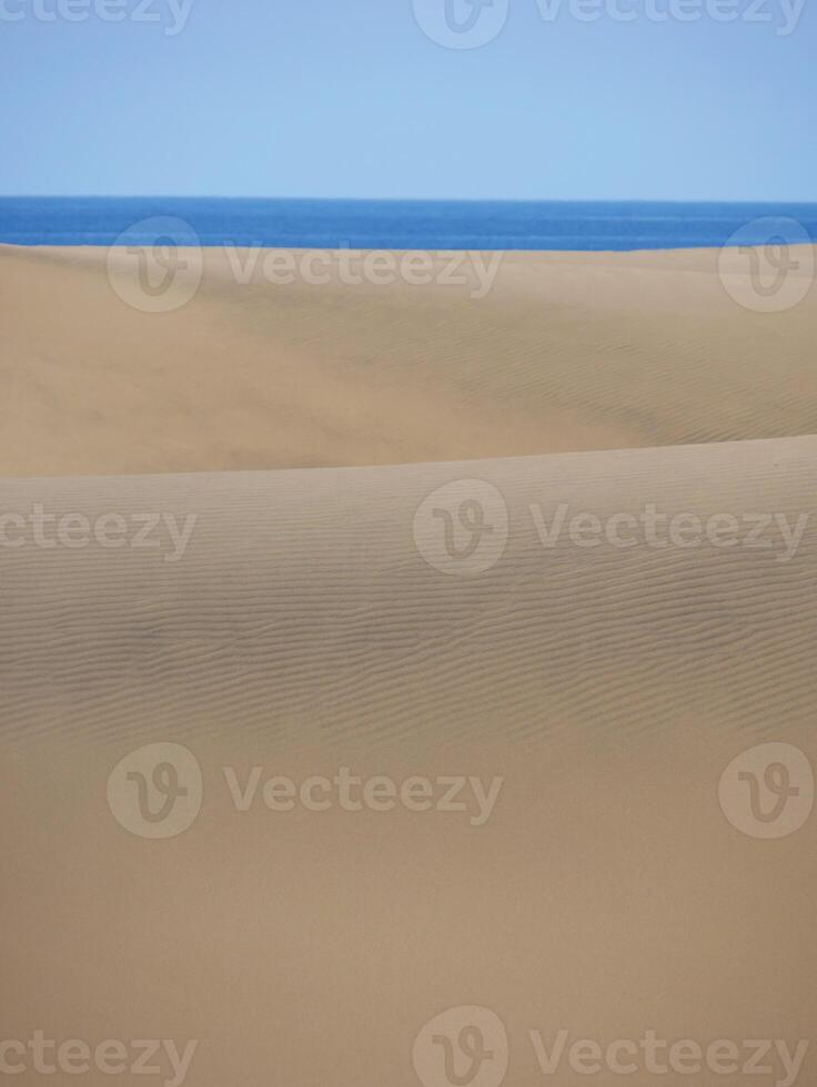Sand textured pattern with copy space close up in Maspalomas, Gran Canaria. Abstract background wallpaper. Sand waves in a desert dune at the background of the sea photo