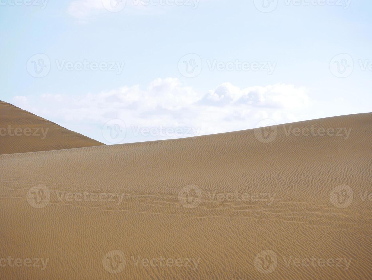 Sand textured pattern with copy space close up in Maspalomas, Gran Canaria. Abstract background wallpaper. Sand waves in a desert dune against the sky photo