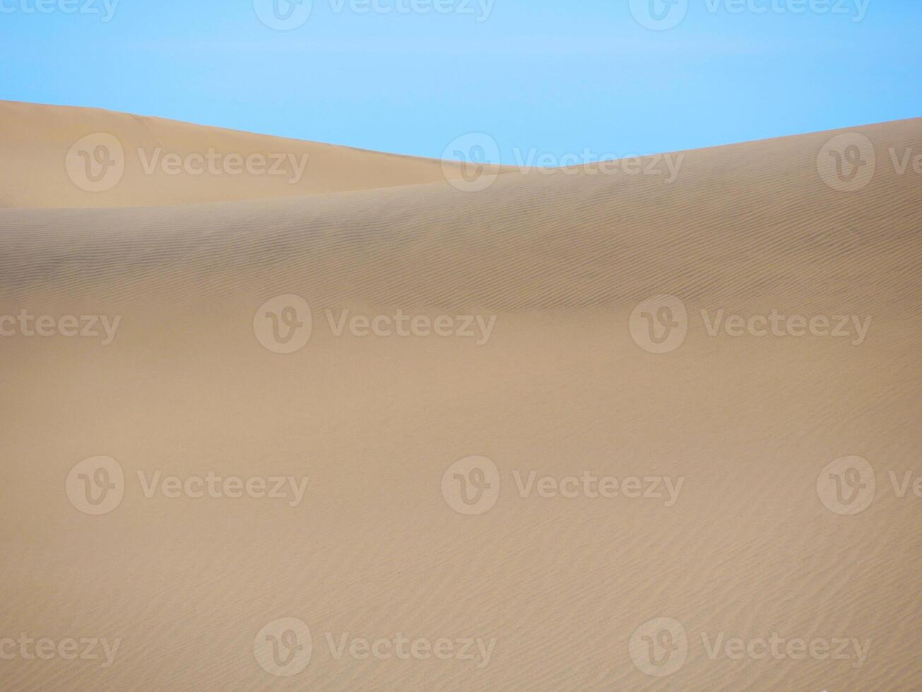 Sand textured pattern with copy space close up in Maspalomas, Gran Canaria. Abstract background wallpaper. Sand waves in a desert dune against the sky photo