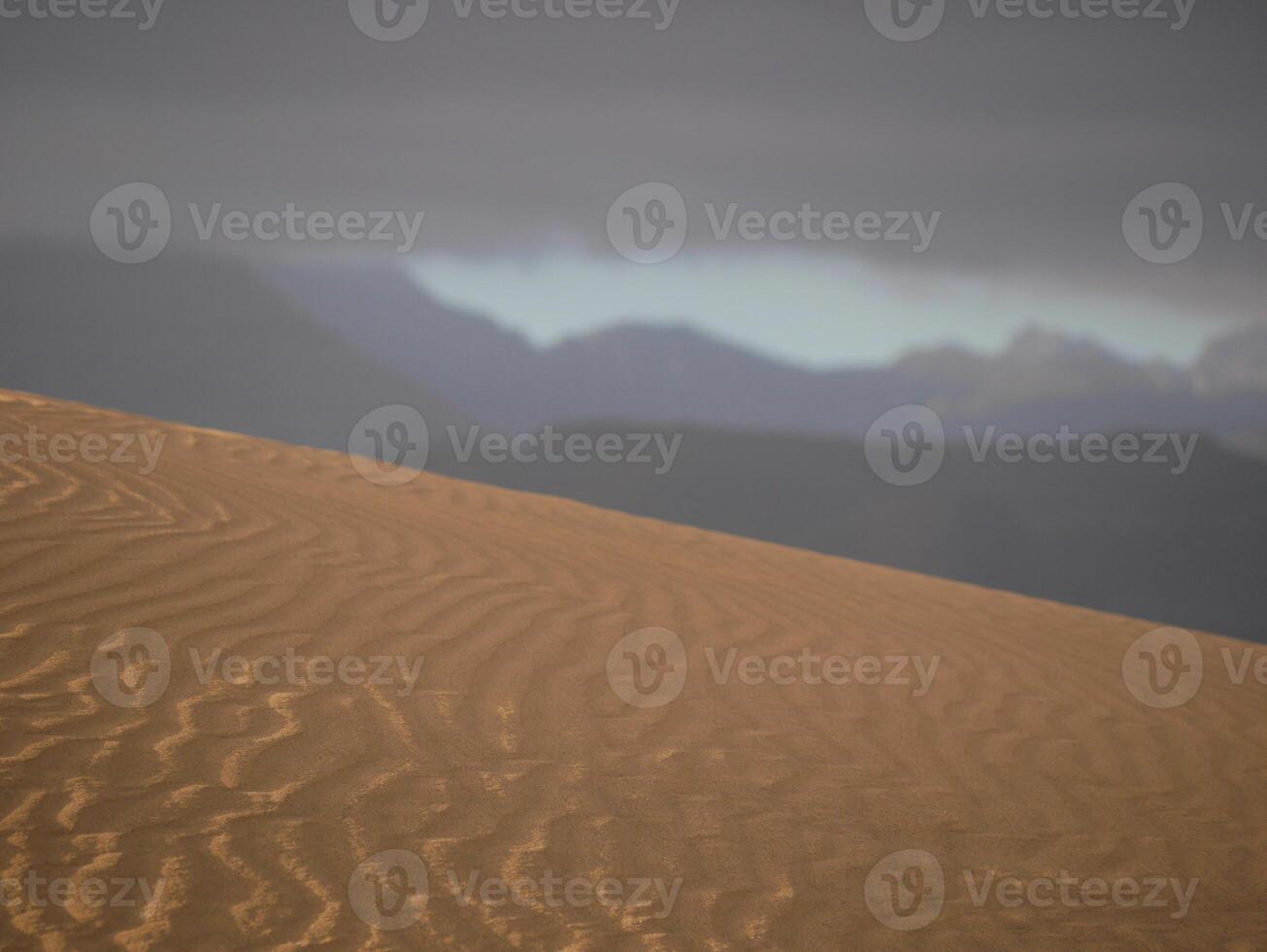 Sand textured pattern with copy space close up in Maspalomas, Gran Canaria. Abstract background wallpaper. Sand waves in a desert dune against the sky photo