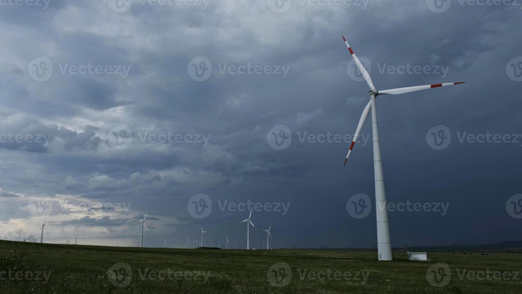Windmill or wind turbine on wind farm in rotation photo