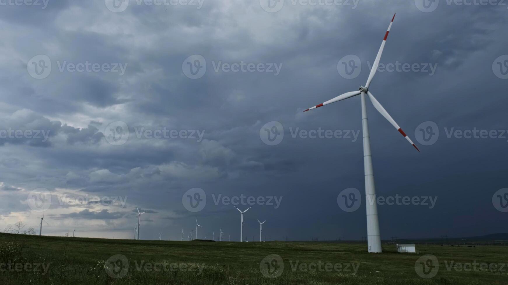 Windmill or wind turbine on wind farm in rotation photo