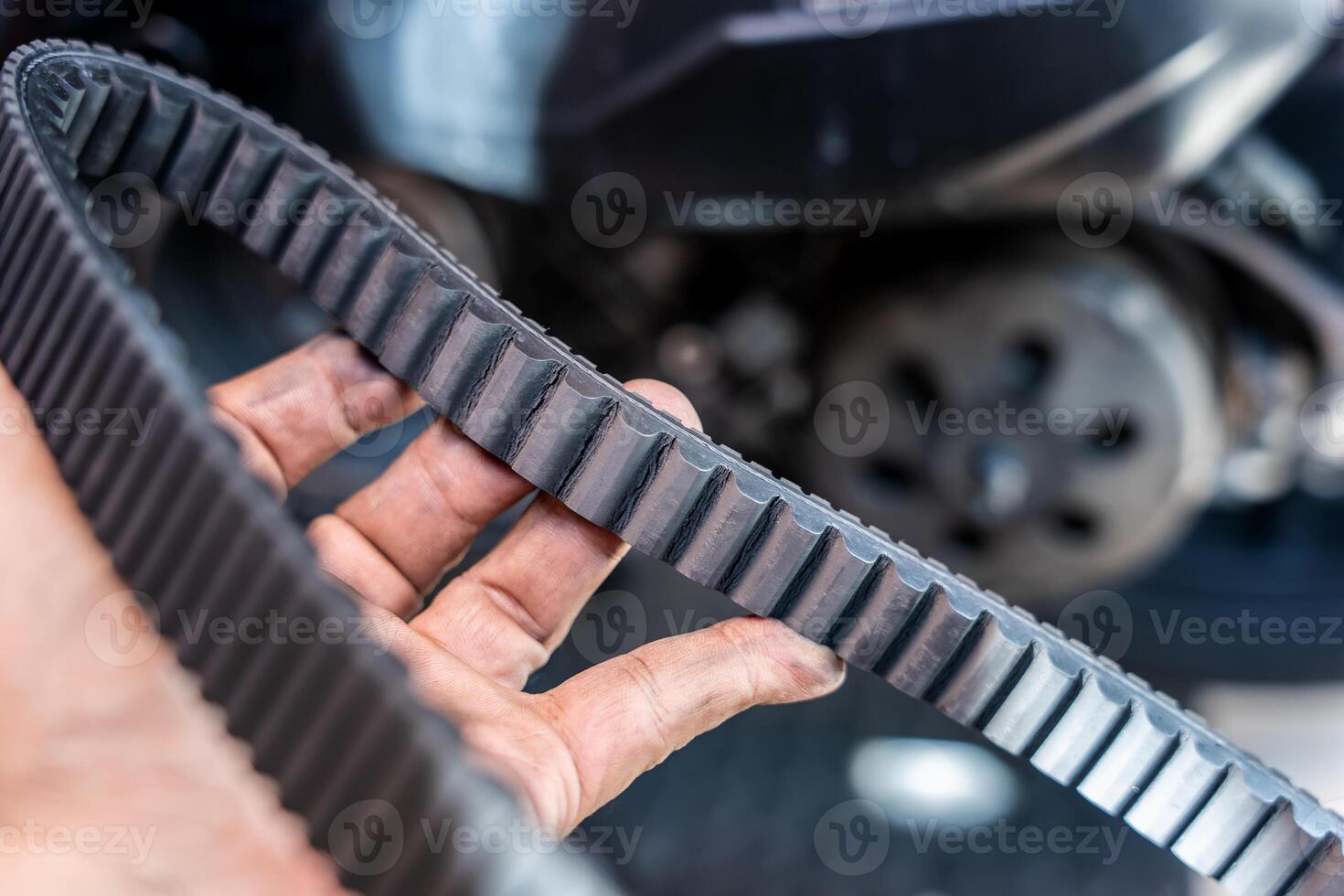 Motorcycle mechanic check the condition of motorcycle transmission belt or Drive belt ,working at garage, maintenance and repair motorcycle concept photo
