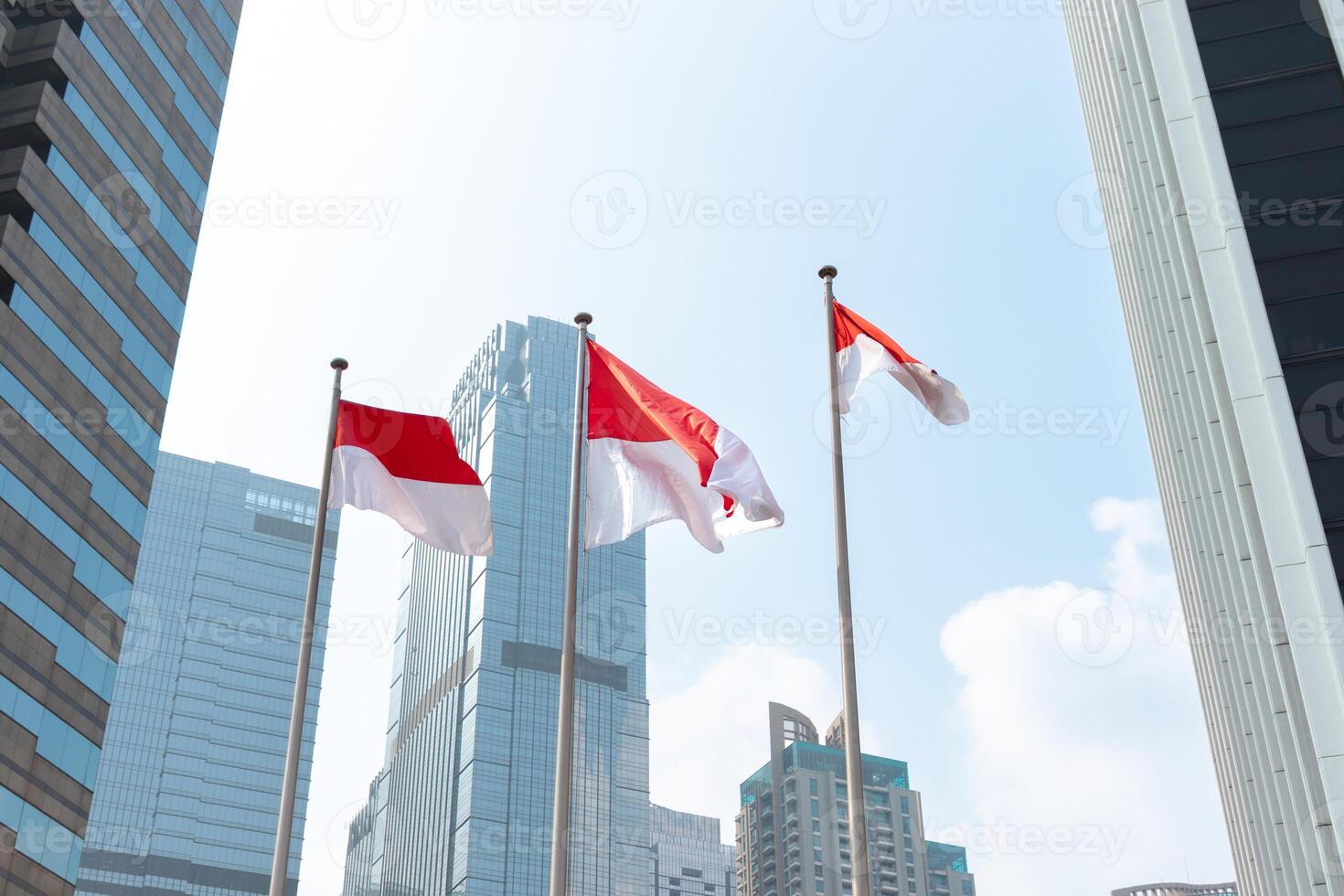 Indonesian flags waving in the wind in front of modern office building. After edits. photo