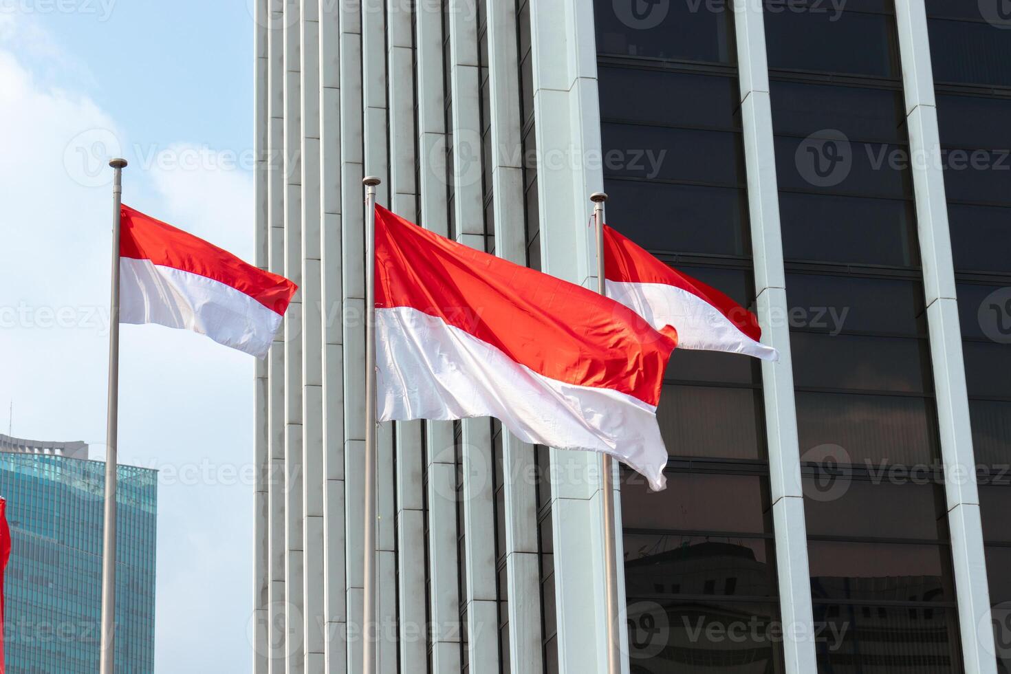 Indonesian flags waving in the wind in front of modern office building. After edits. photo
