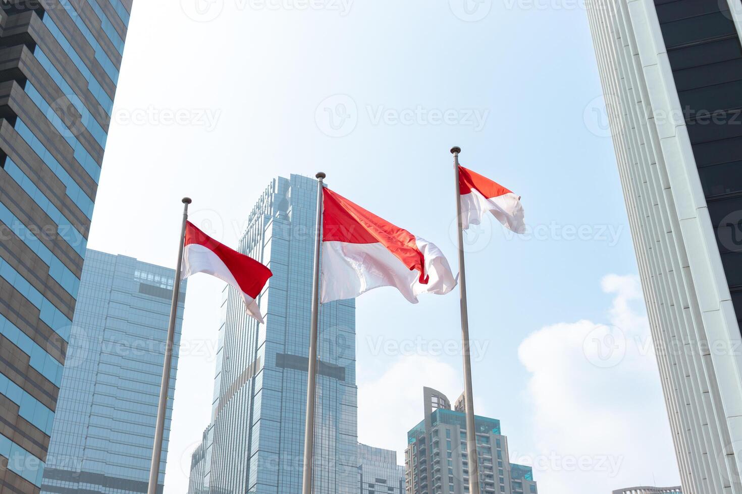 Indonesian flags waving in the wind in front of modern office building. After edits. photo