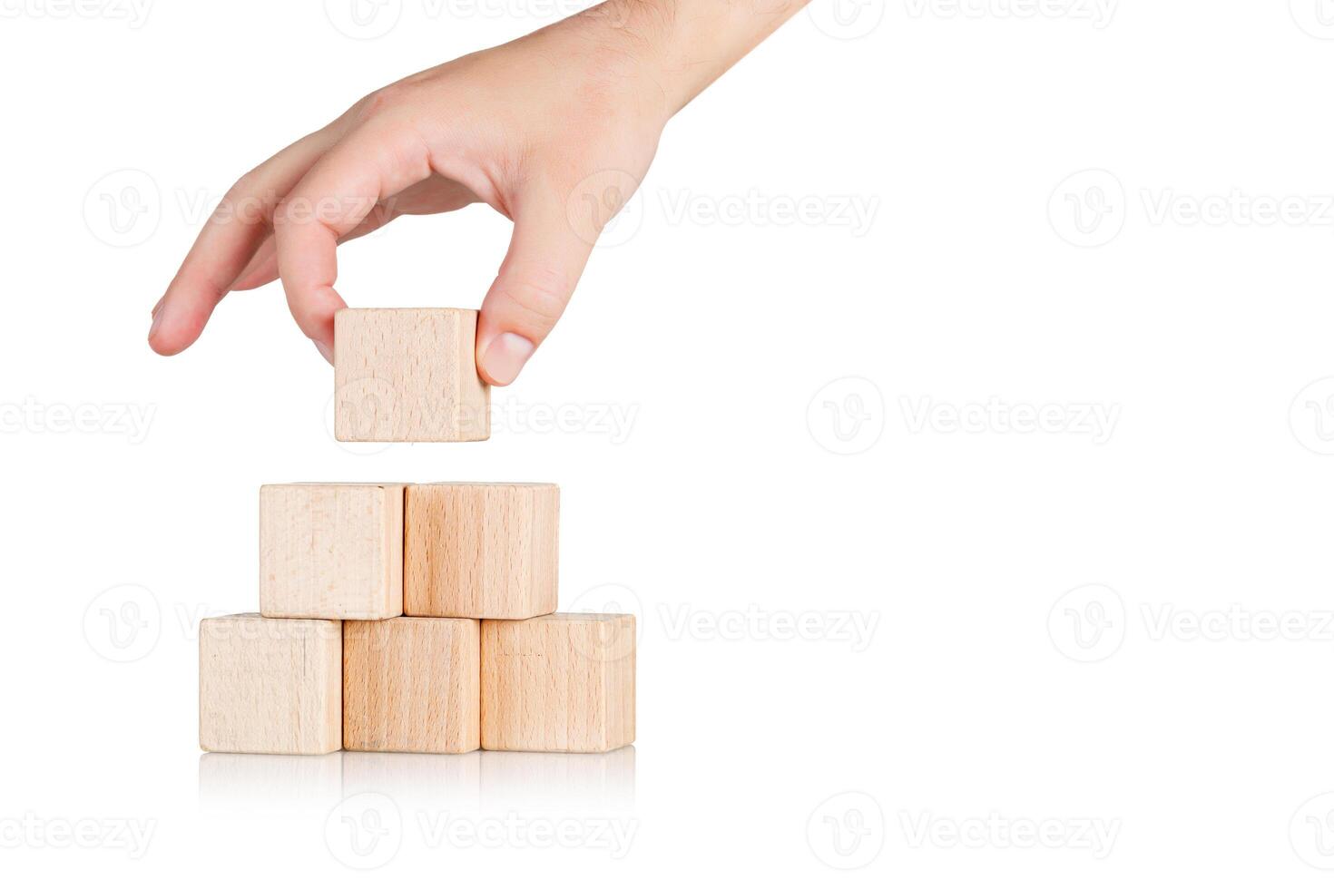wooden cubes in the form of a pyramid with a hand on an isolate white background photo