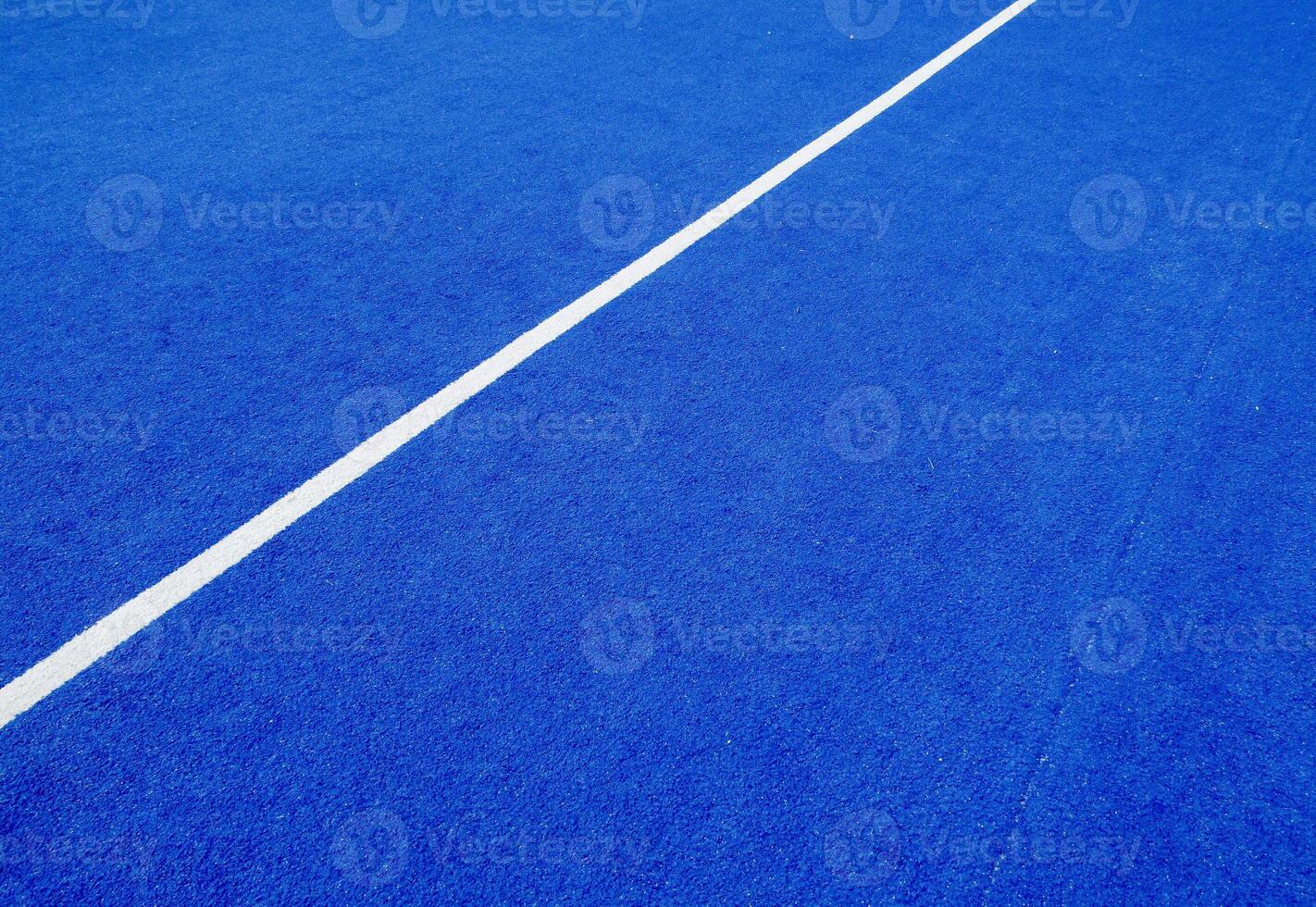 View of the net and the centre line of a blue paddle tennis court. Racket sports photo