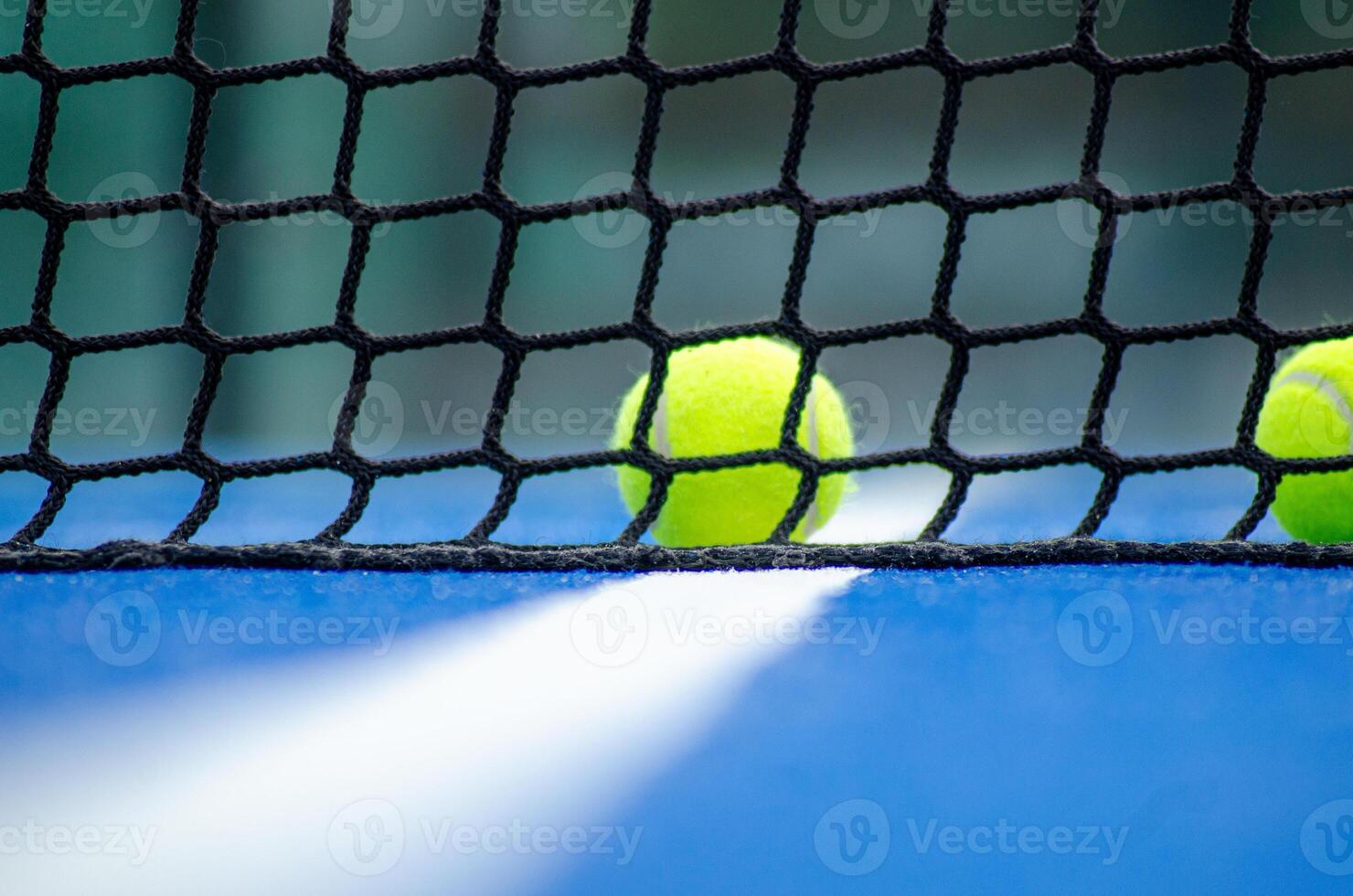 three paddle tennis balls behind the net of a paddle tennis court, background for racket sport concept photo