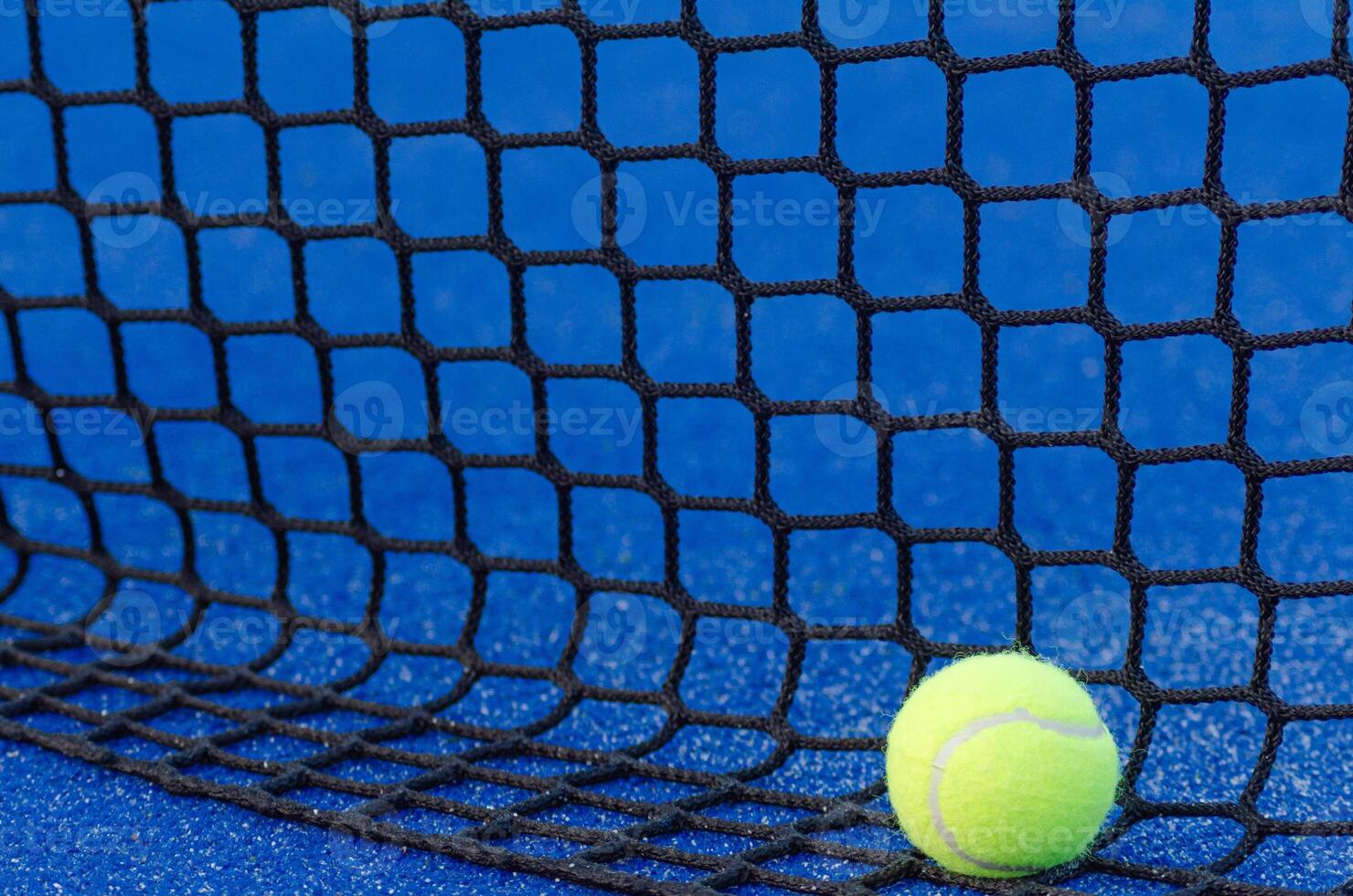 a ball at the base of a padel court net, racket sport background concept photo