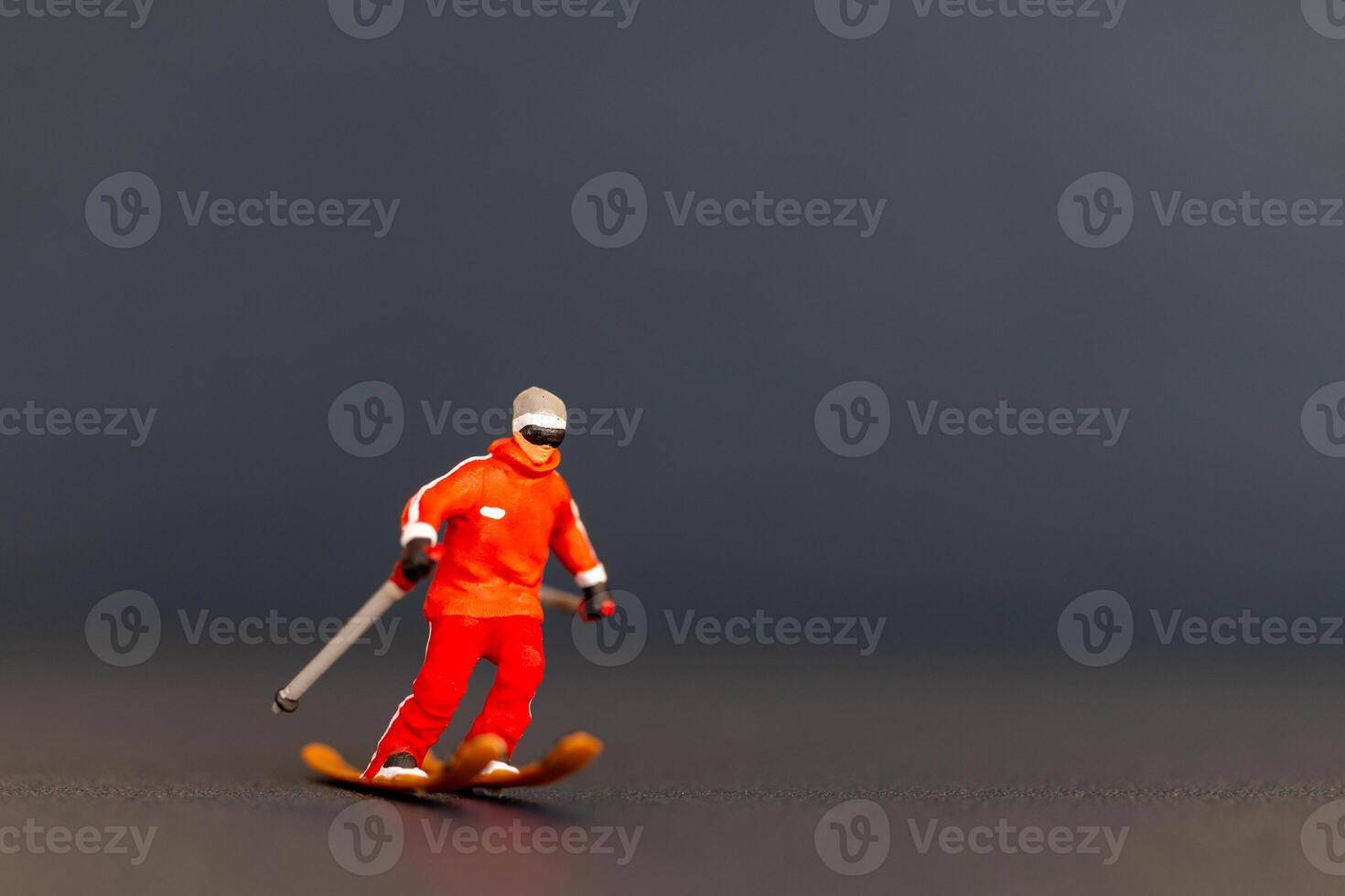 Miniature figurine of a skier is detailed with vibrant colors, set against a dark blurred background photo