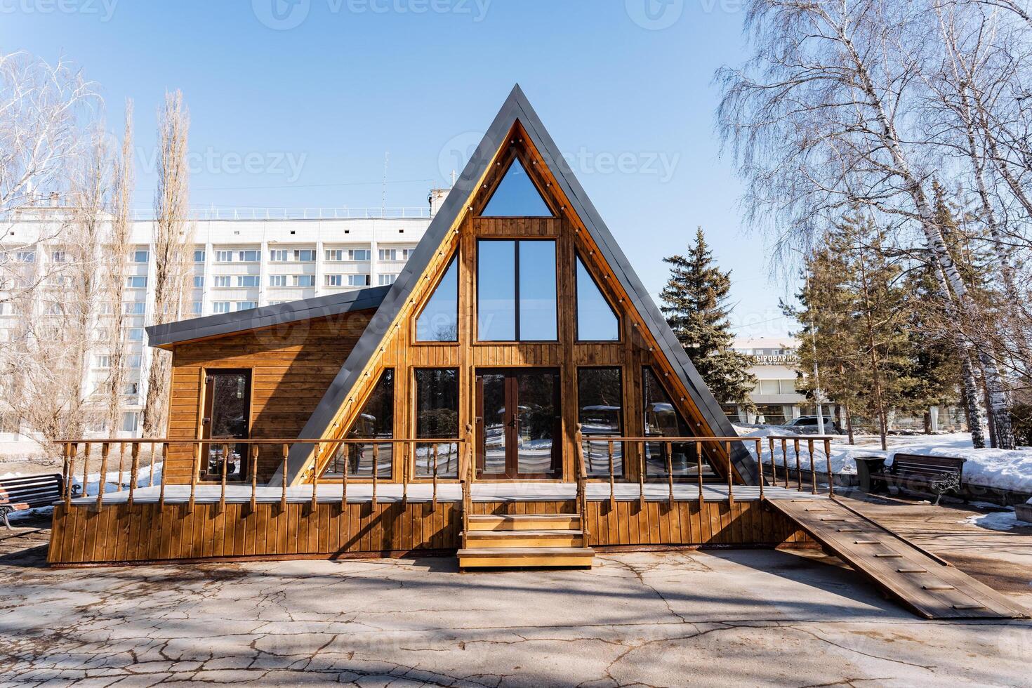 Cottage with triangular roof, lots of windows. Wood siding, on spacious land lot photo