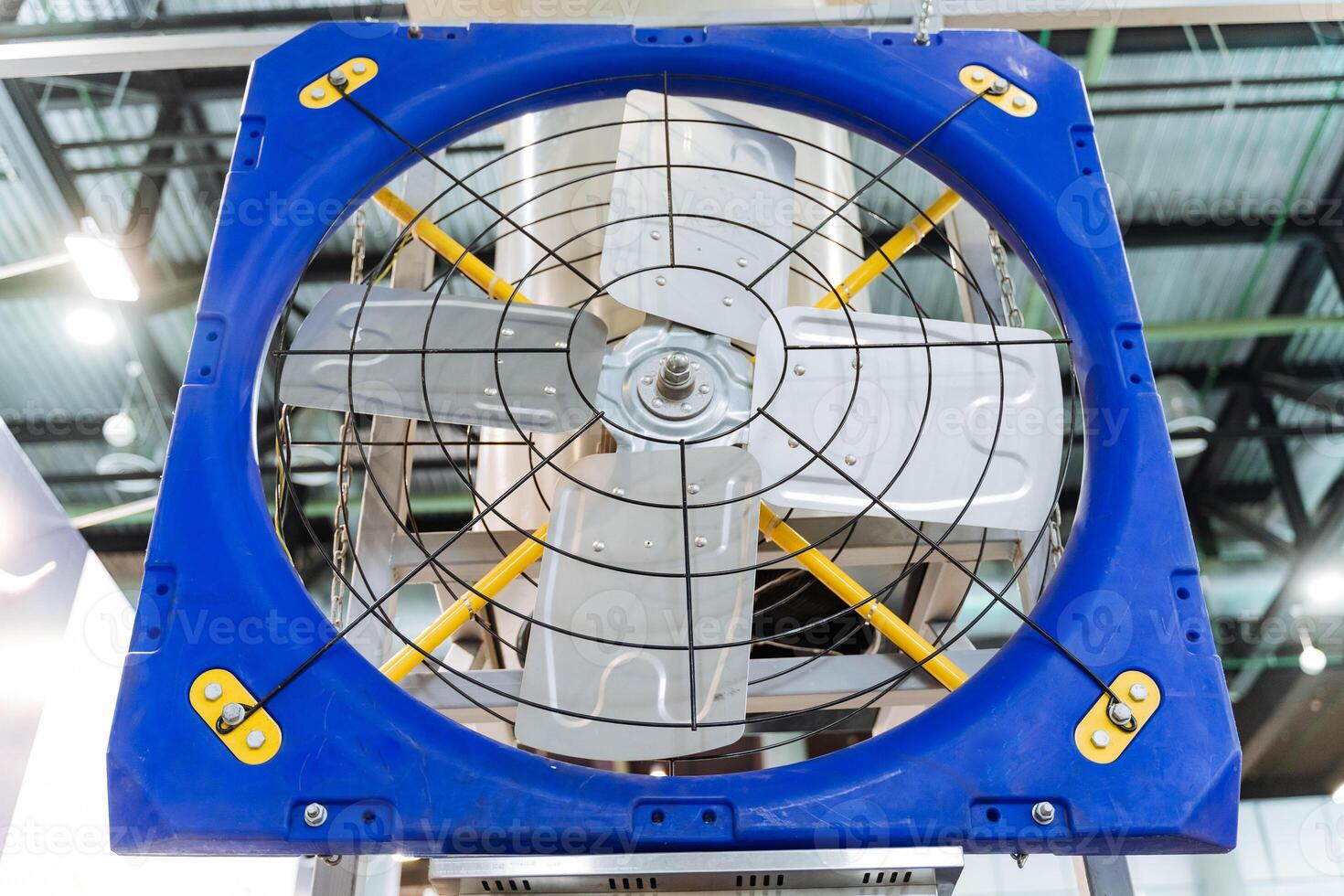 An electric blue and yellow fan hangs in the building photo