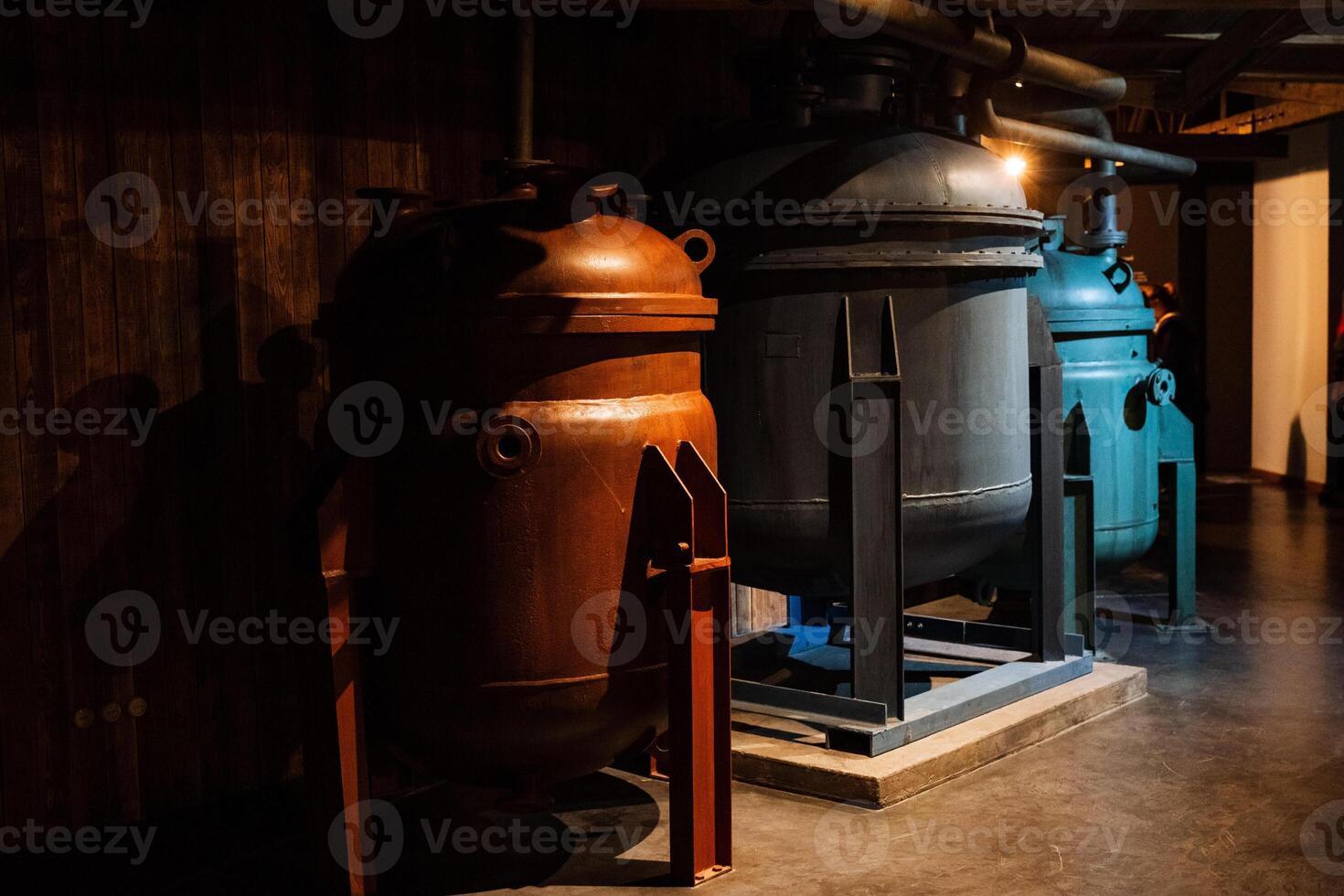 Two large metal tanks sit in a dark room next to each other photo