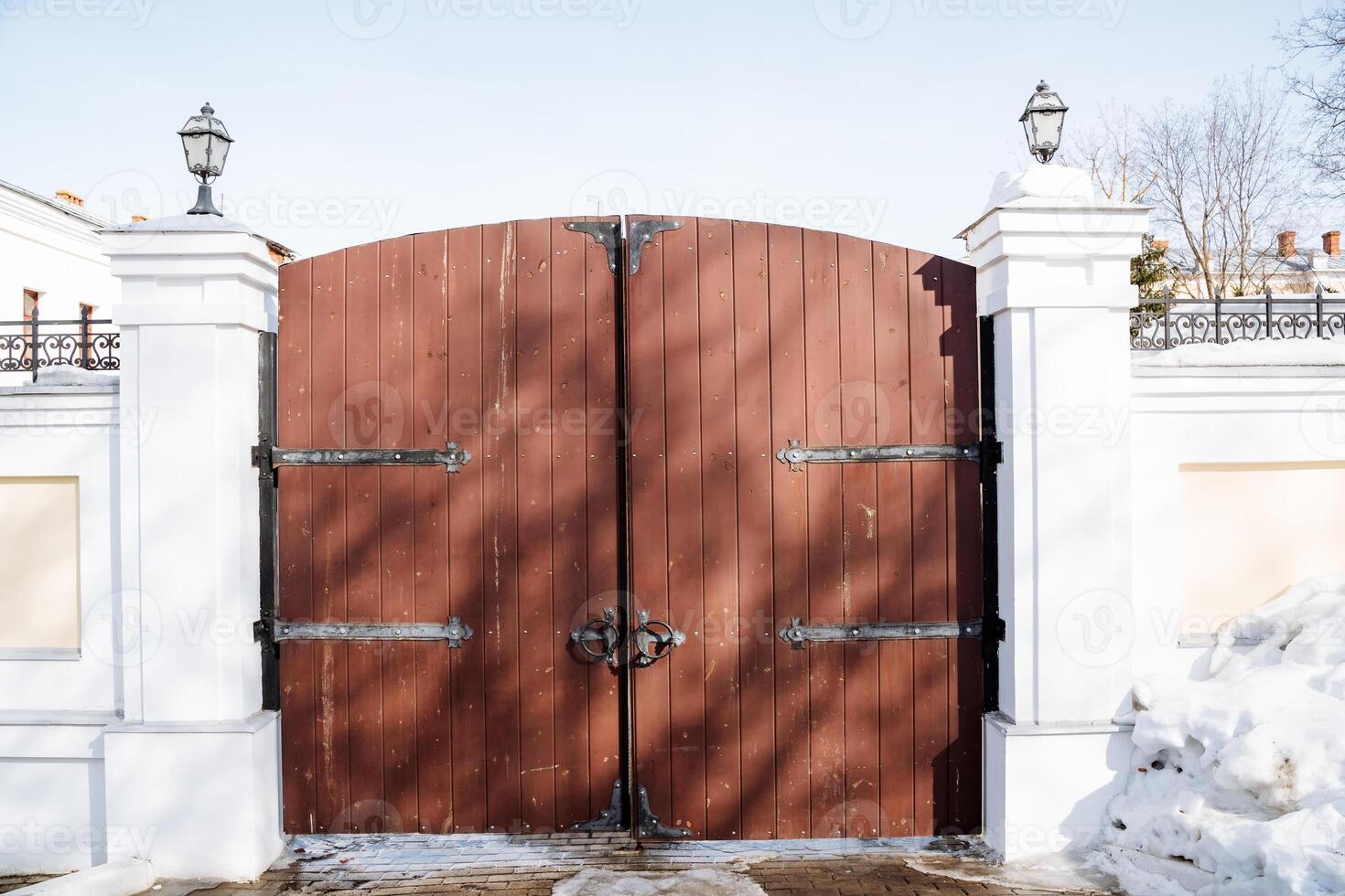 Wooden gate on snowy land lot, enclosed by white wall photo