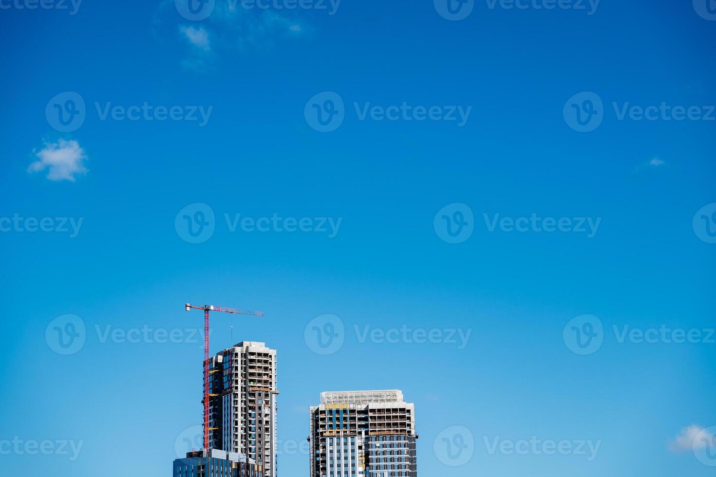 Skyscraper under construction with crane, against a backdrop of blue sky photo