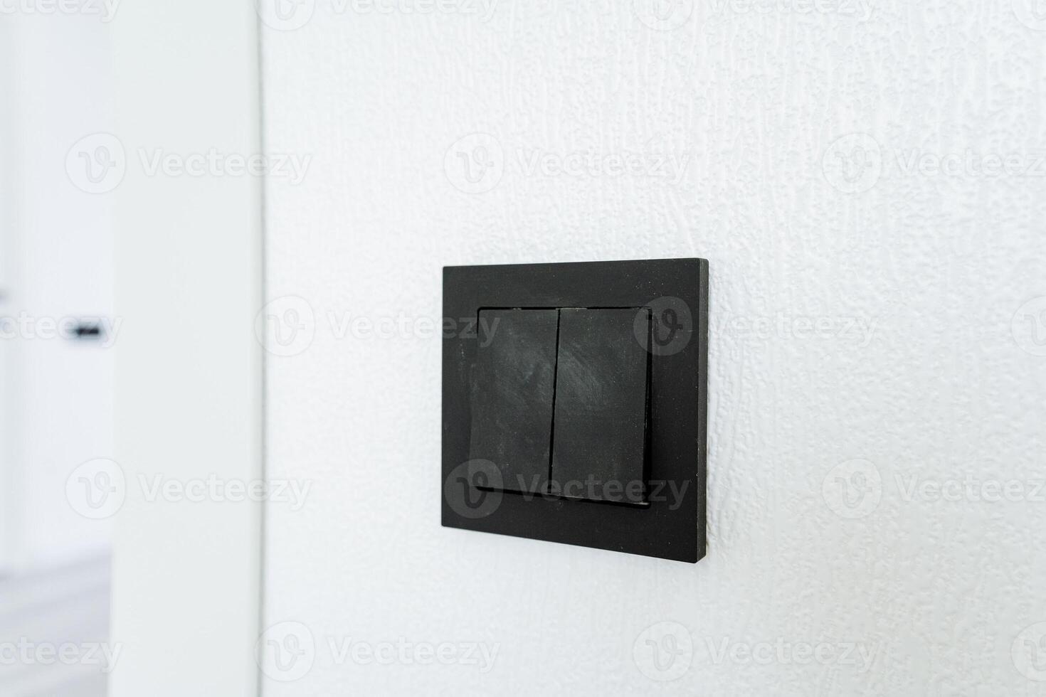 A black light switch is mounted on a white wall in a room with a television set photo