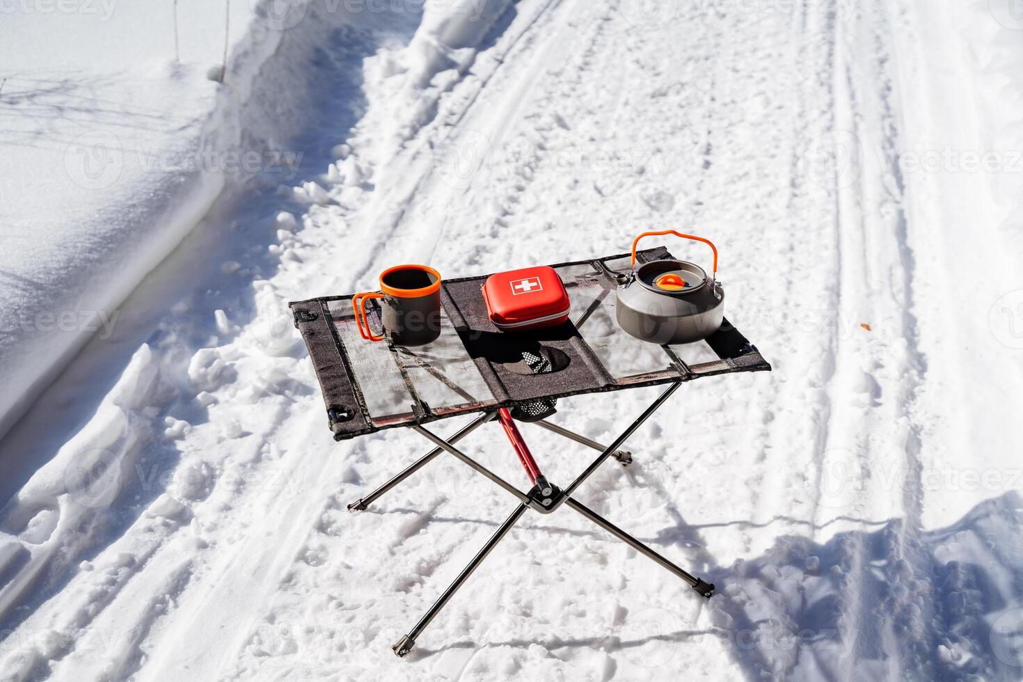 Camping utensils standing on the table in the forest, red first aid kit, folding camping table. photo
