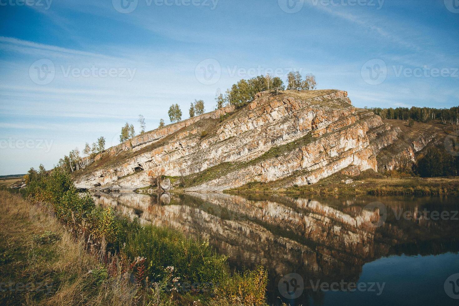 A lake surrounded by a field with a mountain backdrop photo
