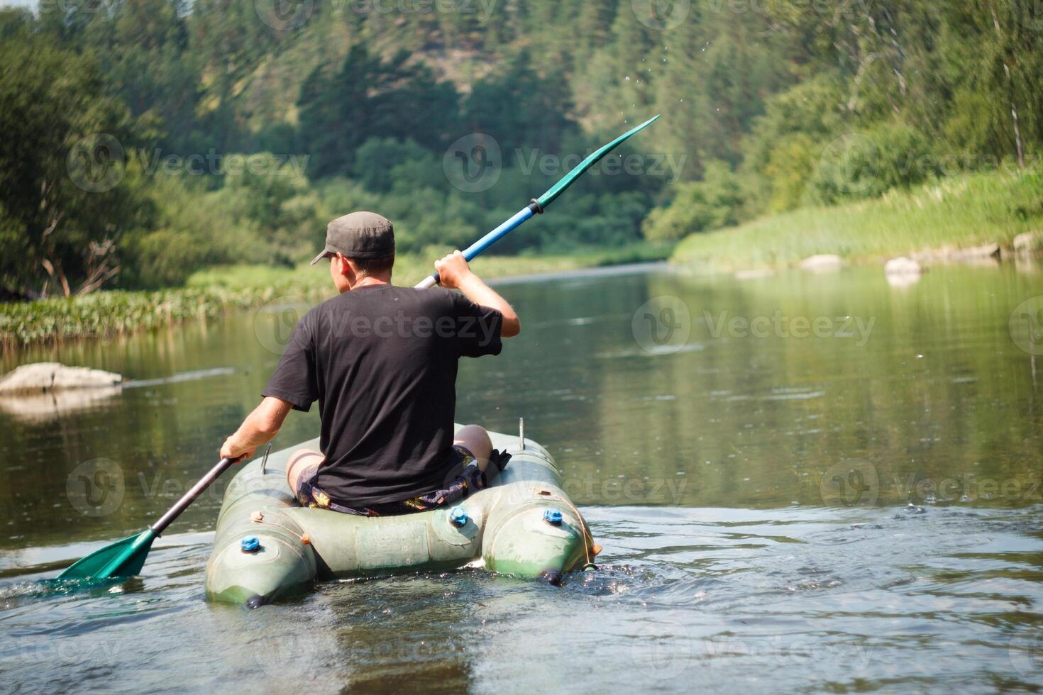 A man paddles a kayak down a river, enjoying the scenic watercourse photo