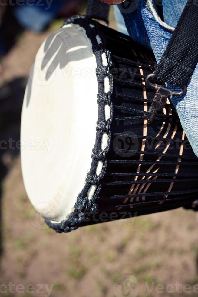 Person with a hand drum strapped around their shoulder photo