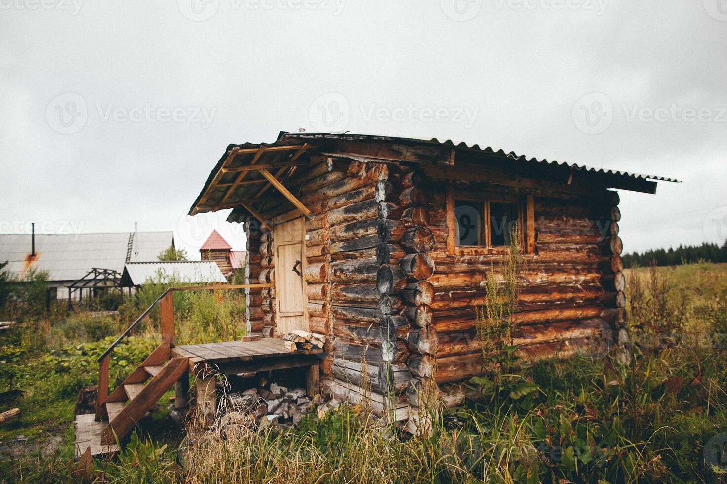 a small wooden cabin is sitting in the middle of a grassy field photo