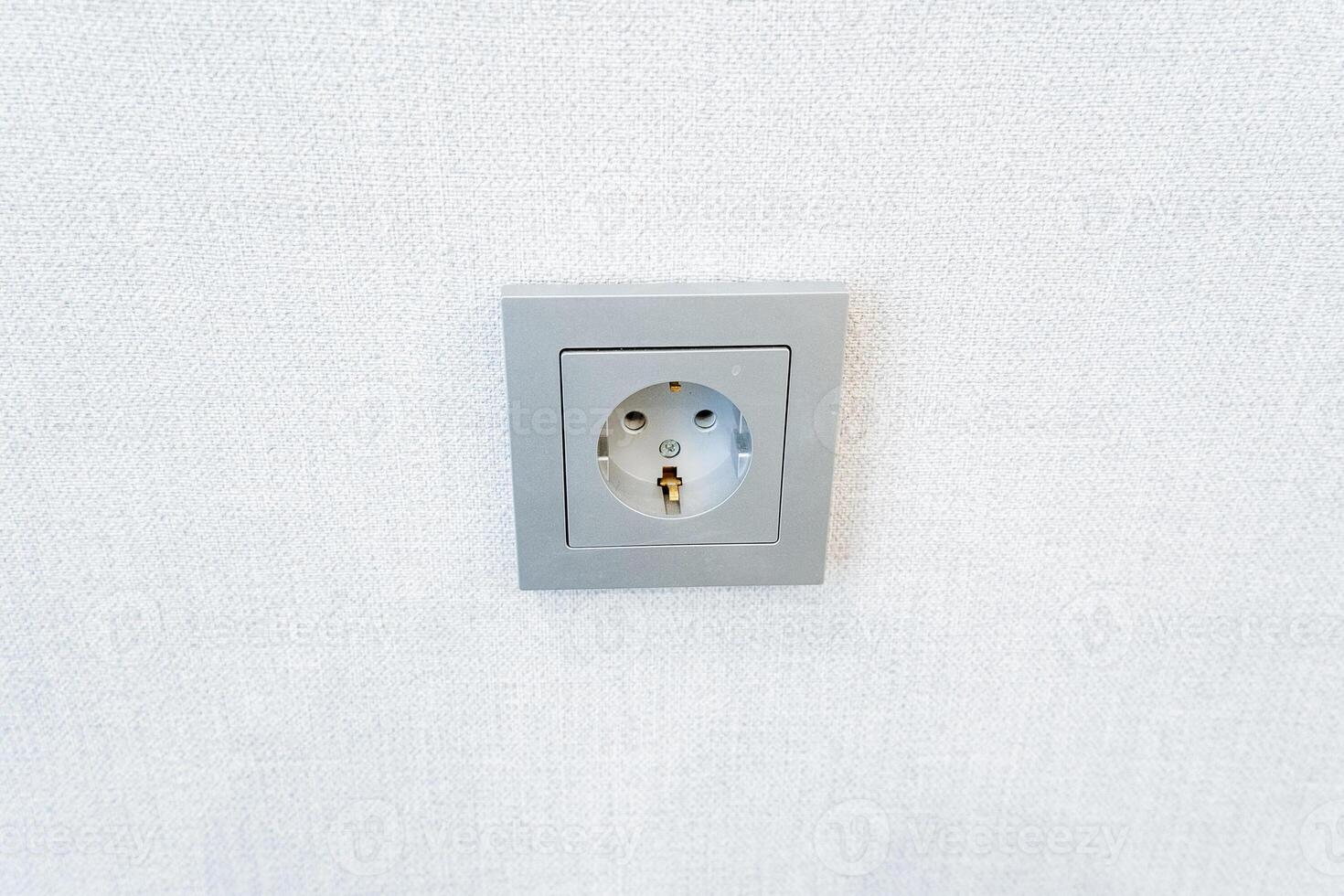 A grey wall socket blending into a white wall, resembling a minimalistic artwork photo