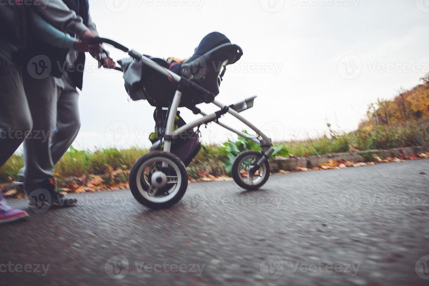 a man rolling a stroller on asphalt road with tire and wheel photo