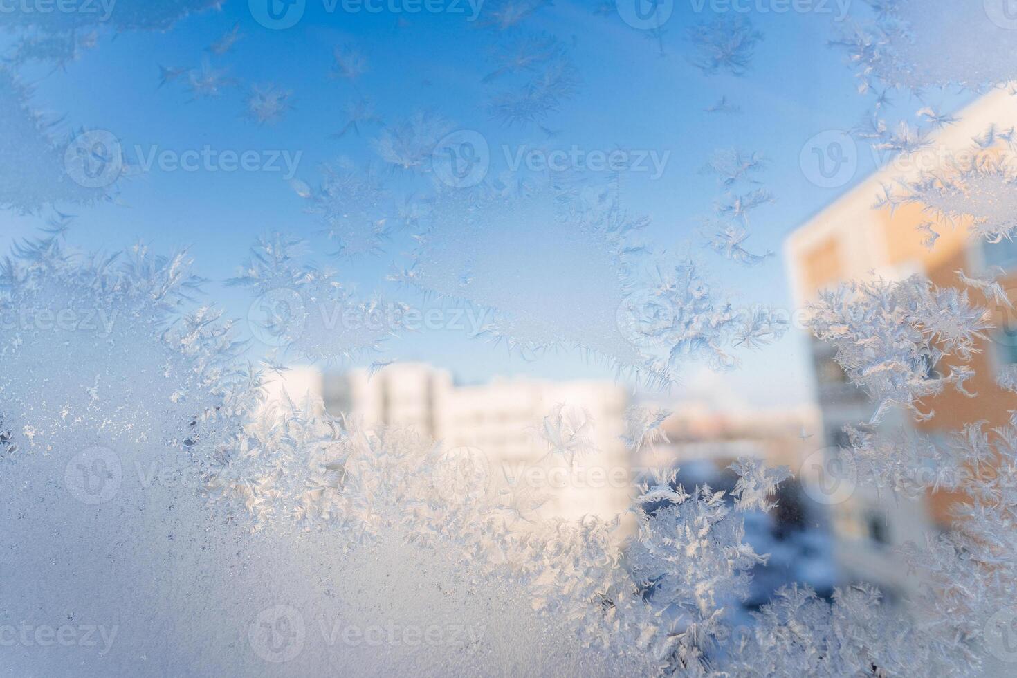 Frozen snowflakes on the window, frost drawing its patterns on the glass, cold season, winter outside the window. photo