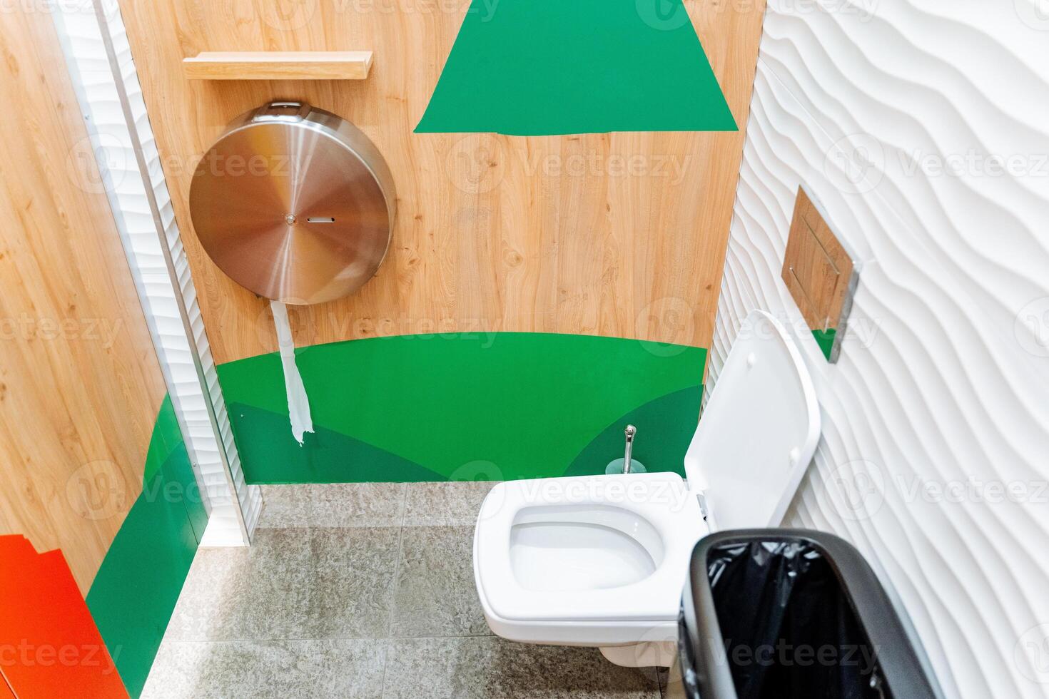 Internal toilet cubicle, white toilet bowl hanging, toilet paper in a metal case, men's room in a shopping center. photo