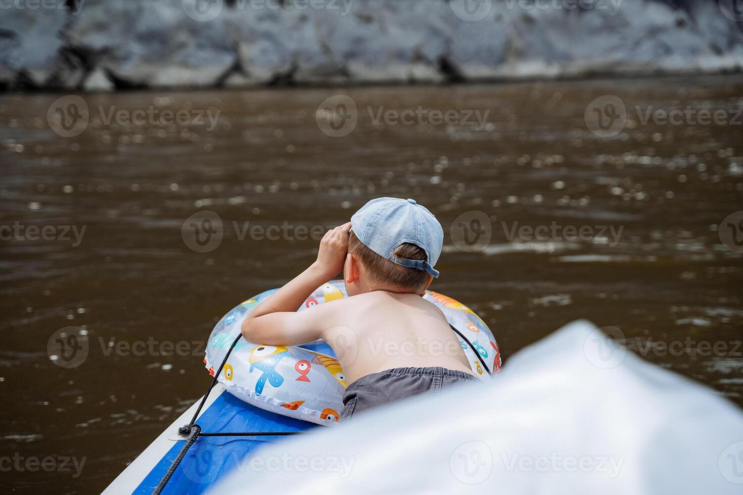 A little boy lies on the bow of a boat sunbathing in the sun, a child's bare back, a vacation on the river, a children's vacation in the summer in nature. photo