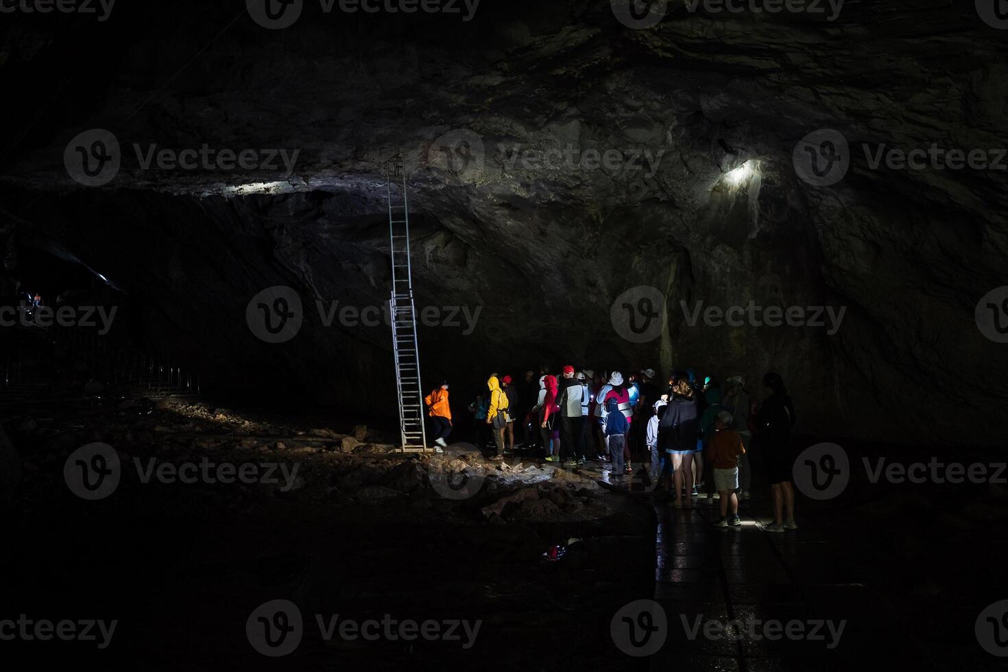 In a large cave there is a staircase leading to the course on the ceiling of the vault, a group of tourists visited the cave complex. photo