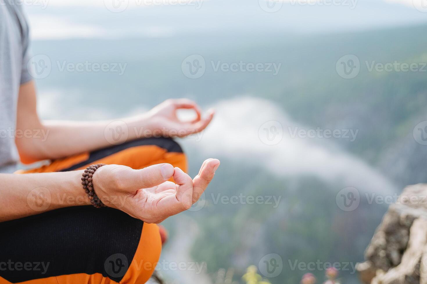 Hands fingers folded in mudra yogic practice, the guy meditates sitting in the mountains against the background of clouds, the silence of the inner world. photo