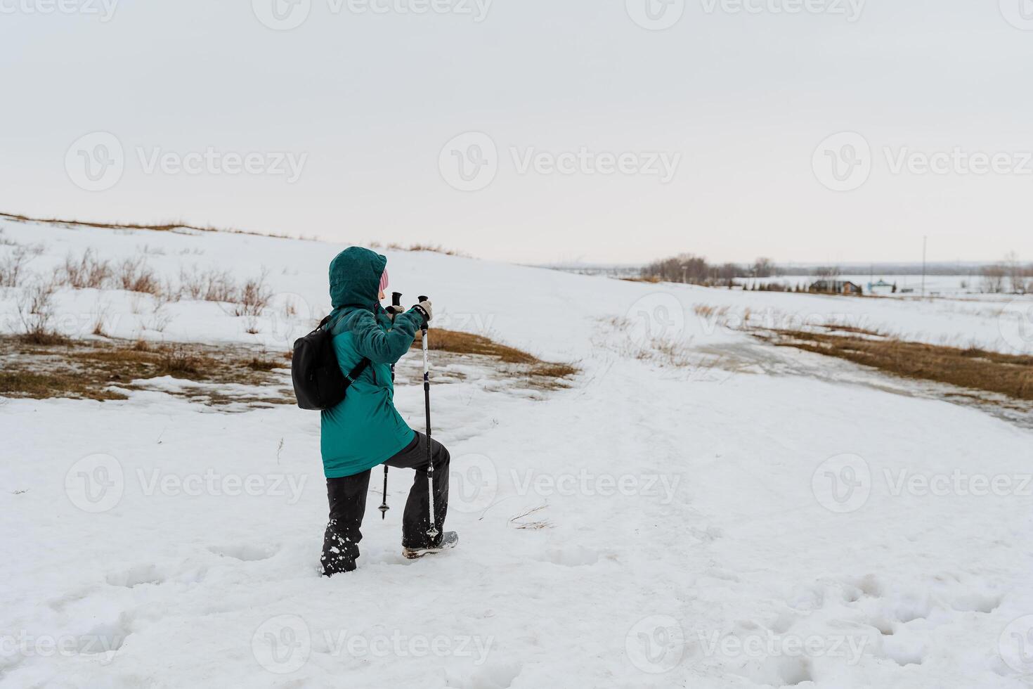 A person walks in the snow with sticks, Nordic walking in winter, winter hiking in cold weather, a tourist travels through the forest. photo